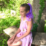 Girl wearing colorful pink & purple clip in hair extensions sitting on a bench