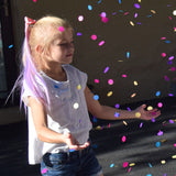 Girl wearing colorful hair extensions for kids catching confetti